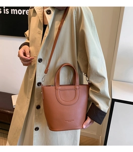 Detailed shot of brown litchi pattern leather bucket bag with top handles and strap