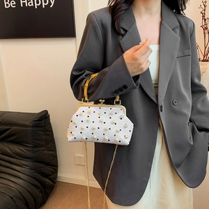 Polka dot handbag with bamboo handle, pearl details and chain strap worn by a model