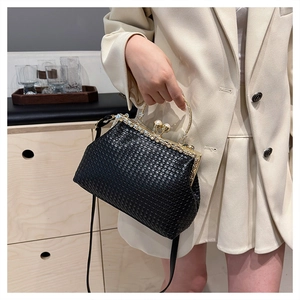 Macro view of woven texture handbag with pearl rhinestone clasp and gold metal handle