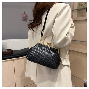 Detail of elegant black woven evening bag with rhinestone clasp worn on shoulder