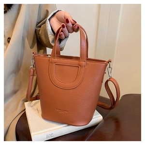 Detailed macro of caramel lychee grain leather bucket bag with dual handles and strap