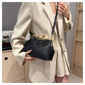 Detail of woven black leather handbag with gold metal frame and pearl clasp closure