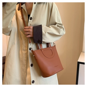 Caramel leather bucket bag with litchi texture paired with a classic beige trench coat