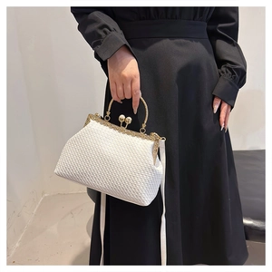 Detail of white woven texture bag with gold frame and decorative pearl clasp closure