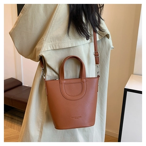 Detail of brown lychee leather bucket bag with top handle and adjustable shoulder strap