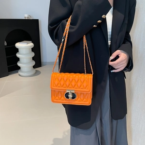 Sac bandoulière matelassé orange vif avec fermoir doré et bandoulière chaîne sur veste