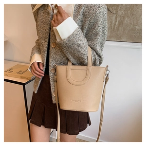 Chic beige lychee grain bucket bag styled with a tweed jacket and casual skirt