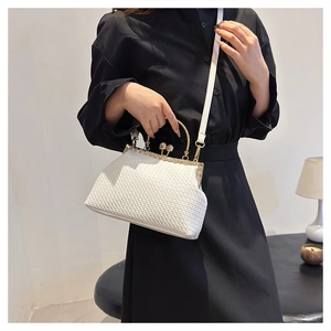 Detail of white woven evening bag featuring gold metal handle and elegant pearl clasp