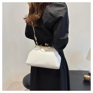 Detailed view of a white woven crossbody bag with gold metallic clasp worn by a model