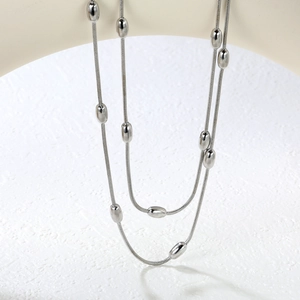 Gros plan d'un collier double épaisseur en maille serpent avec perles ovales lisses