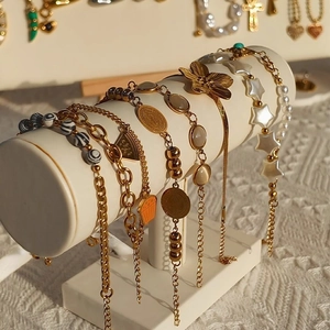 Gold multi-layered charm bracelet set with star and coin charms on a white stand