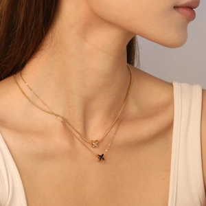 Collier double rang plaqué or 18K avec pendentif en X sur le décolleté du modèle