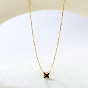 Détail macro du pendentif en X doré avec émail noir sur chaîne en acier inoxydable 18K