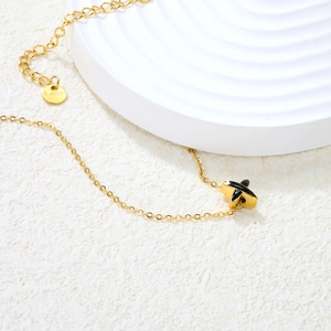 Détail macro d'un collier en acier inoxydable doré avec pendentif noir en X