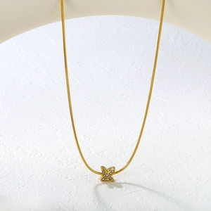 Gros plan d'un pendentif en X doré serti de cristaux scintillants sur une chaîne fine
