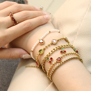 Layered gold heart and cherry charm bracelets with pearl accents and ruby gemstone ring