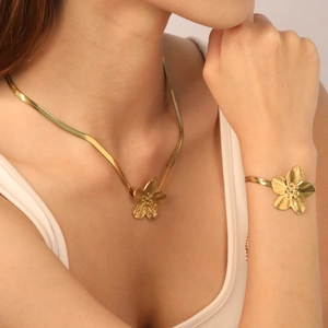 Detailed view of a gold floral necklace and bracelet set with brushed metal texture