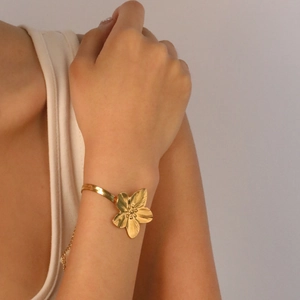Golden flower petal bracelet with sleek snake chain on female wrist in warm lighting