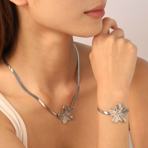 Detail of silver petal pendant necklace and snake chain bracelet set on skin