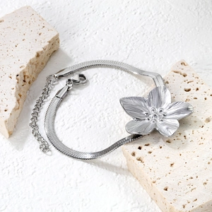 Detailed macro view of silver flower pendant on a snake chain stainless steel bracelet