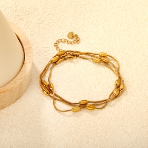 Dettaglio della collana a tre strati in acciaio inossidabile dorato con perline ovali