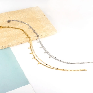 Dettaglio di cavigliere minimaliste in oro e argento con ciondoli a fulmine e catena regolabile