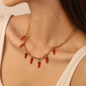Collier en acier doré avec des pendentifs piment rouge porté par un mannequin de mode