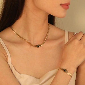 Detailed view of gold evil eye jewelry set featuring textured chain and inlaid stones