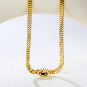 Detailed shot of a thick gold wheat chain necklace with an evil eye charm and black stone