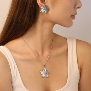 Silver flower jewelry set featuring textured petal necklace and earrings on a model