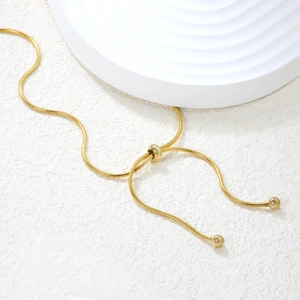 Detail of adjustable 18K gold snake chain with sliding bead closure and smooth finish