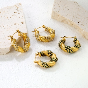 Détail de boucles d'oreilles torsadées en forme de C dorées avec cristaux émeraude et clairs