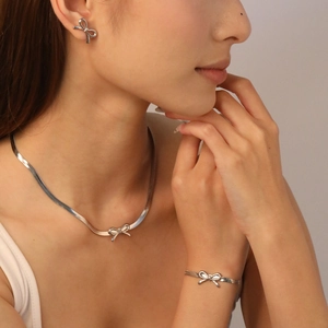 Detailansicht eines silbernen Schleifen-Schmucksets mit Halskette, Armband und Ohrringen