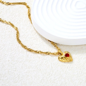 Lava textured gold heart necklace with red crystal pendant on elegant stone base