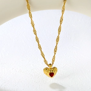 Luxury gold lava heart necklace with red gemstone pendant on white textured stand
