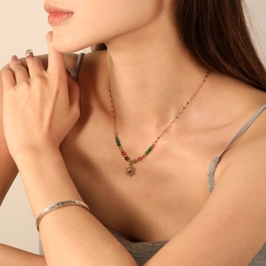 Detail of vintage sun pendant necklace with colorful beads on a model with gold jewelry
