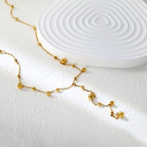Détail du long collier à pompons en acier inoxydable plaqué or 18 carats avec perles