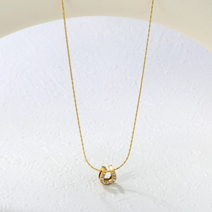Macro shot of gold U-shaped horseshoe pendant with inlaid sparkling crystals on a fine chain