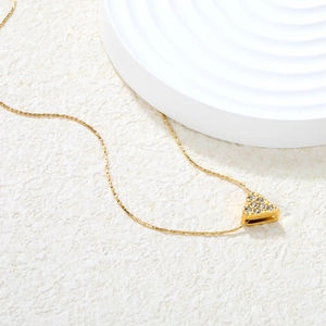 Elegant gold U-shape necklace with sparkling rhinestone heart pendant on a white textured base