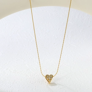 Detail of gold heart pendant necklace featuring sparkling inset zirconias on white stone