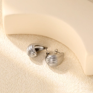Makro-Detail von silbernen Edelstahl-Ohrsteckern mit strukturiertem radialem Fächerdesign