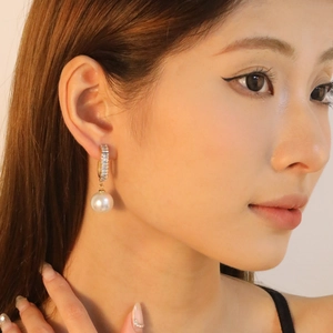 Elegant gold pearl drop earrings with rectangular zircon studs worn by a female model