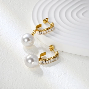 Detail of 18k gold earrings with rectangle zircon and large white pearls on white tray