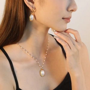 Detail shot of elegant faux pearl necklace and matching earrings set on a female model