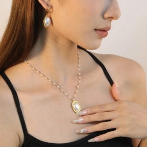 Detail of elegant imitation pearl necklace and earrings set worn by a female model