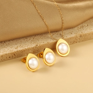 Detailed view of elegant gold pearl jewelry set with necklace and stud earrings on stone