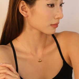 Detailed close-up of a 18K gold plated shell pendant necklace worn by a model