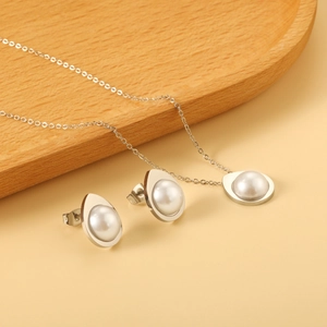 Detail of teardrop pearl pendant necklace and earrings set on a wooden tray