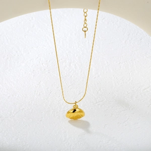 Golden shell pendant necklace with O-chain on white stone background elegant jewelry