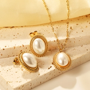 Close-up of gold-plated pearl necklace and earrings set on silk and stone background
